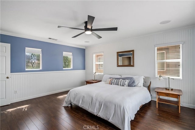 bedroom with a wainscoted wall, ornamental molding, wood-type flooring, and visible vents