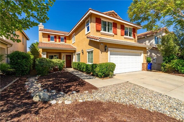 view of front of house with a tiled roof, a chimney, concrete driveway, an attached garage, and stucco siding