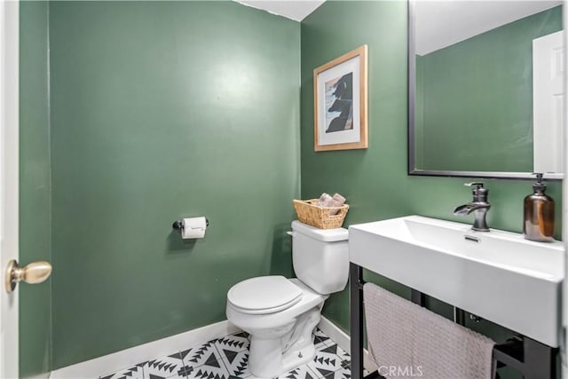 half bathroom with baseboards, tile patterned flooring, and toilet