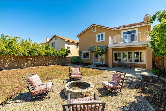 rear view of property with a fenced backyard, stucco siding, an outdoor fire pit, and a balcony