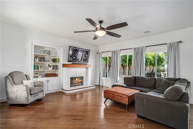 living room featuring a glass covered fireplace, ceiling fan, and wood finished floors