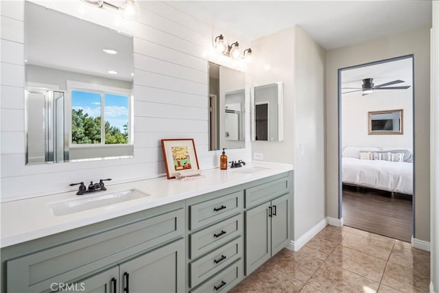 ensuite bathroom featuring a sink, tile patterned floors, a ceiling fan, and double vanity