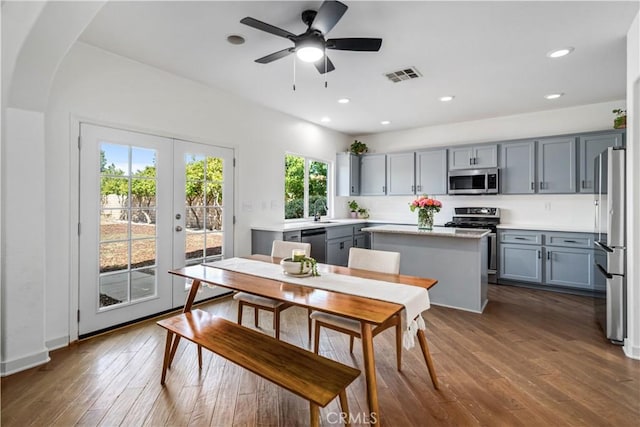 dining area featuring arched walkways, dark wood finished floors, french doors, a ceiling fan, and visible vents