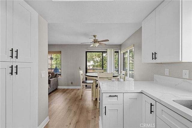 18114 Erik Ct Unit 5131, Canyon Country, CA 91387 - kitchen featuring baseboards, light wood-style floors, a ceiling fan, light stone countertops, and white cabinetry