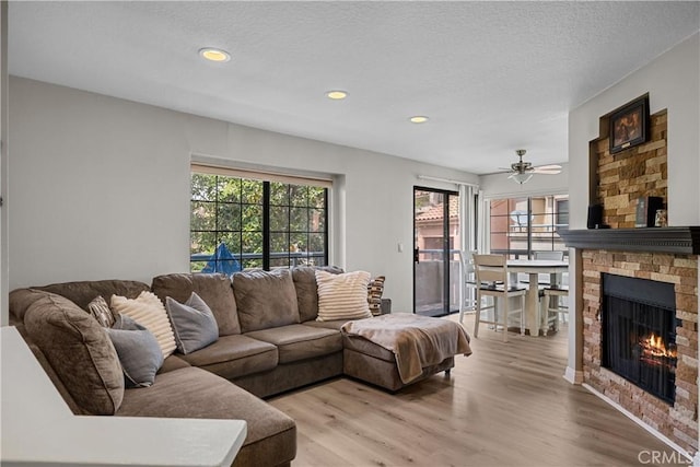 18114 Erik Ct Unit 5131, Canyon Country, CA 91387 - living room with healthy amount of natural light, a stone fireplace, light wood finished floors, recessed lighting, and a textured ceiling