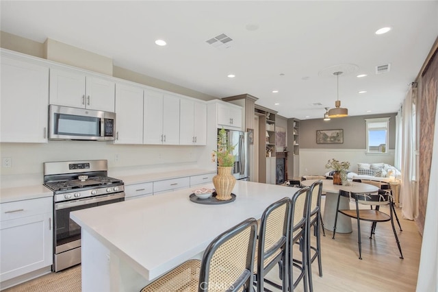 18147 Jupiter Ln, Saugus, CA 91350 - kitchen with stainless steel appliances, light countertops, recessed lighting, white cabinets, and a kitchen island
