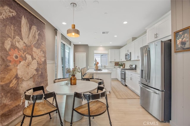 18147 Jupiter Ln, Saugus, CA 91350 - kitchen featuring stainless steel appliances, light countertops, a kitchen island, light wood-type flooring, and white cabinets