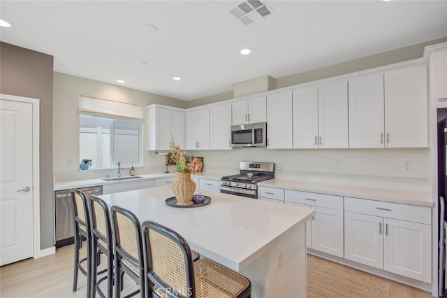 18147 Jupiter Ln, Saugus, CA 91350 - kitchen featuring appliances with stainless steel finishes, a sink, a breakfast bar area, white cabinets, and recessed lighting
