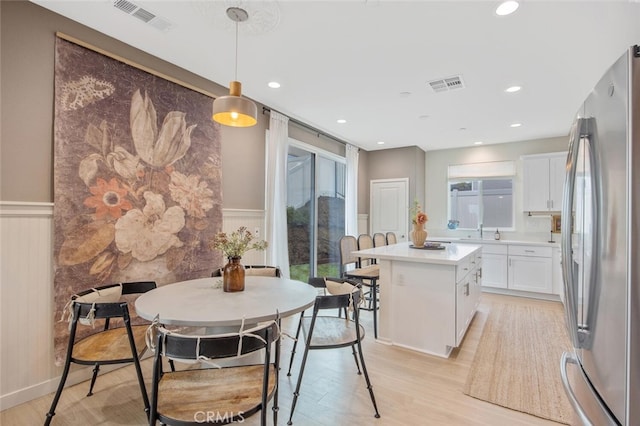 18147 Jupiter Ln, Saugus, CA 91350 - kitchen with freestanding refrigerator, wainscoting, white cabinets, light wood-type flooring, and a kitchen island
