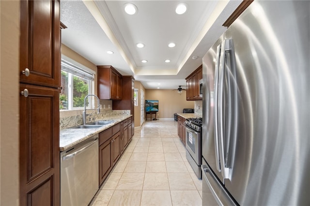 45628 Gleneagles Ct, Temecula, CA 92592 - kitchen featuring a sink, baseboards, light stone counters, a raised ceiling, and stainless steel appliances