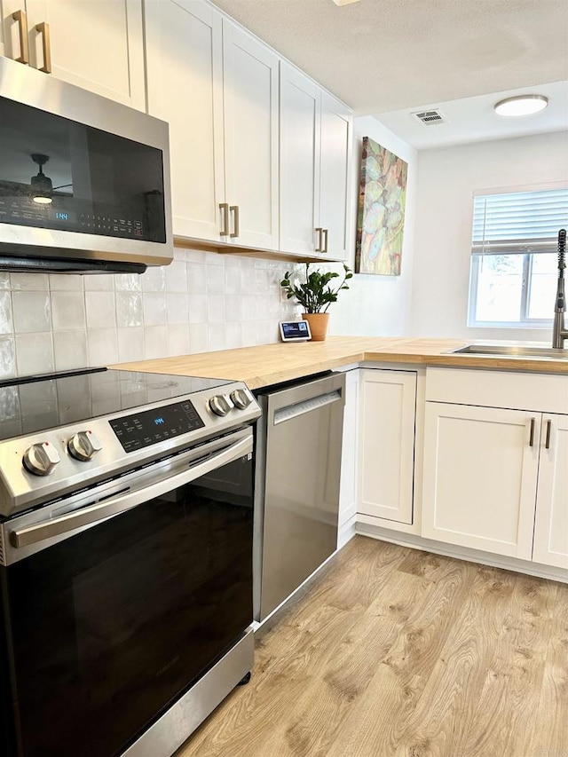 10525 Flora Verda Ct, Santee, CA 92071 - kitchen with decorative backsplash, butcher block countertops, light wood-type flooring, a sink, and appliances with stainless steel finishes