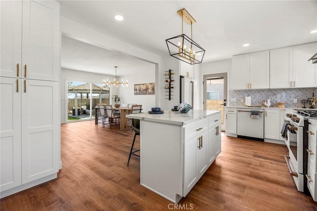kitchen featuring white appliances, white cabinets, dark wood finished floors, backsplash, and a notable chandelier