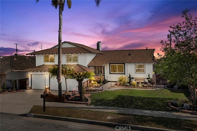 split level home featuring fence, an attached garage, driveway, and a front yard