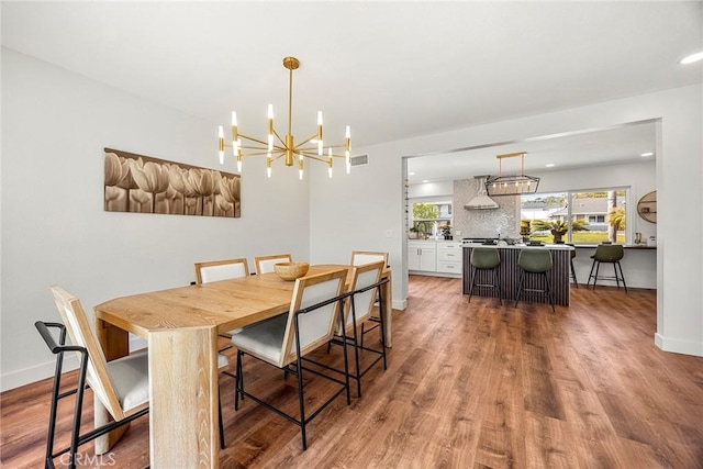 dining area with baseboards, a chandelier, wood finished floors, and visible vents