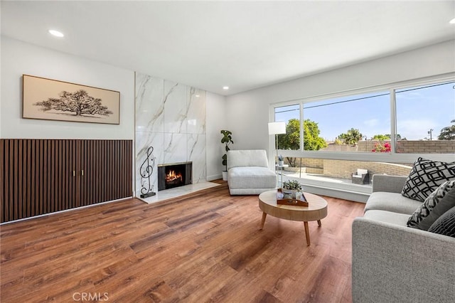 living room with recessed lighting, a high end fireplace, and wood finished floors