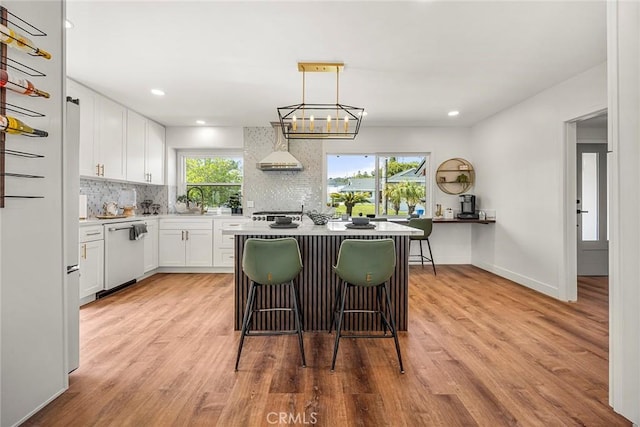 kitchen featuring white cabinets, a sink, dishwasher, backsplash, and a kitchen island