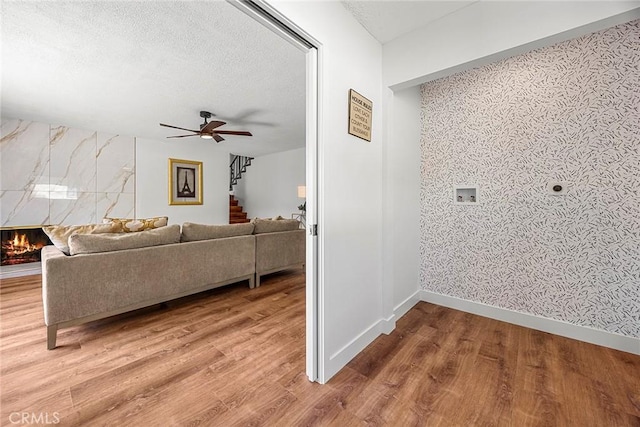 corridor with a textured ceiling, baseboards, wood finished floors, and stairway