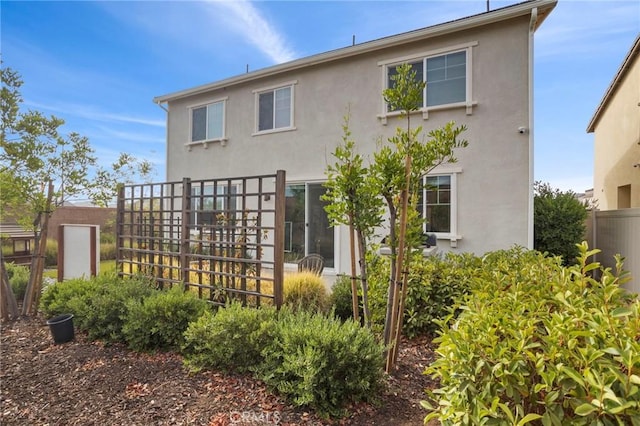 rear view of house featuring fence and stucco siding