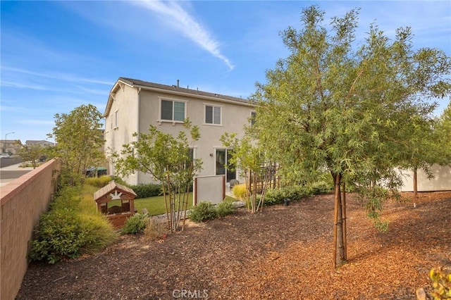 back of property with fence and stucco siding