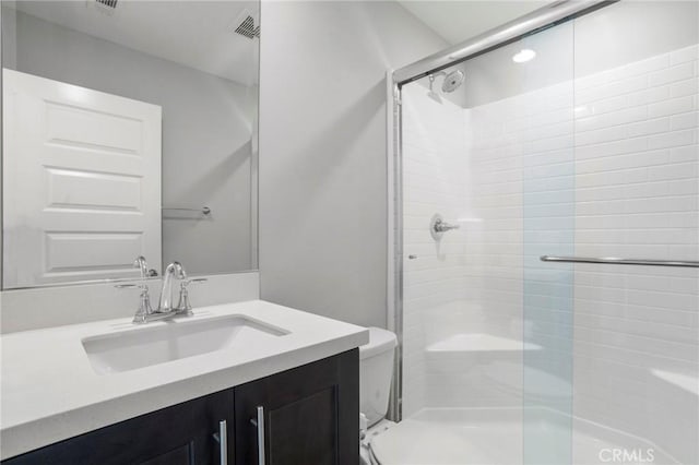 full bathroom featuring vanity, a stall shower, toilet, and visible vents