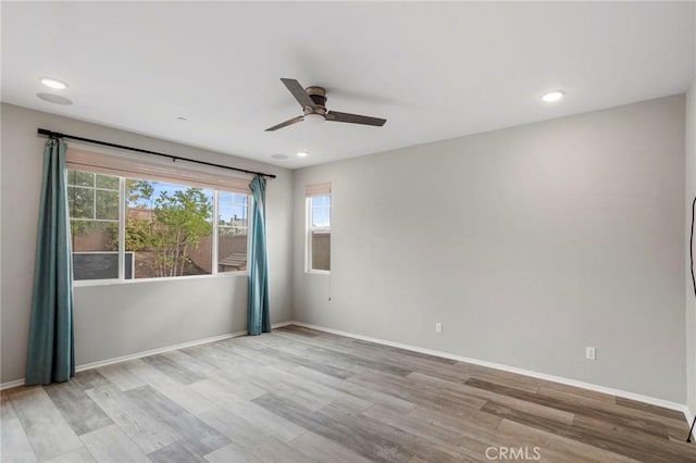 unfurnished room featuring light wood-style floors, baseboards, ceiling fan, and a wealth of natural light