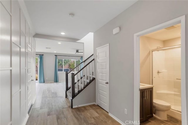 corridor featuring stairway, recessed lighting, baseboards, and light wood-type flooring