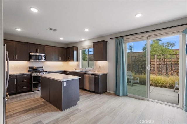 kitchen with light wood-style floors, light countertops, dark brown cabinets, and stainless steel appliances