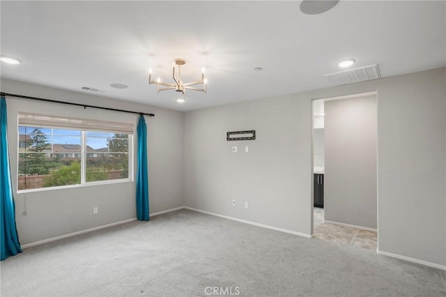 carpeted spare room with baseboards, visible vents, and a chandelier