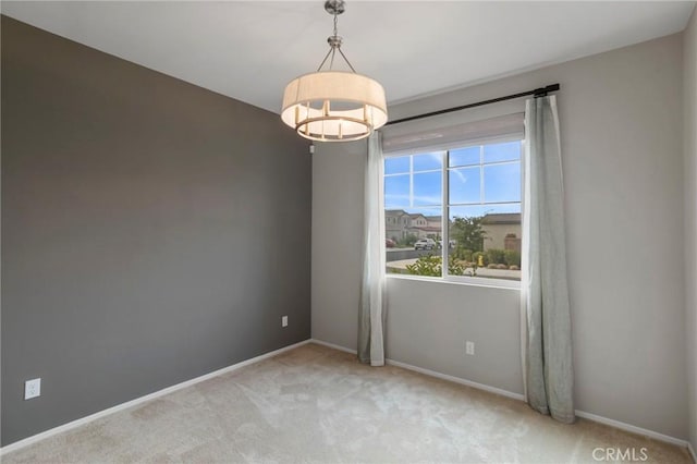 unfurnished room featuring a notable chandelier, light colored carpet, and baseboards