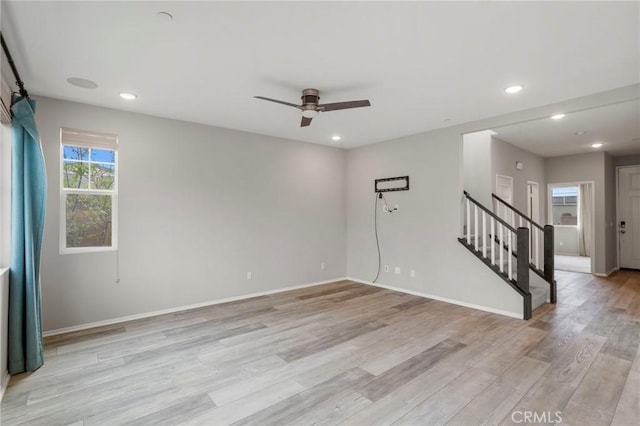 empty room with a ceiling fan, stairway, baseboards, recessed lighting, and light wood-style flooring
