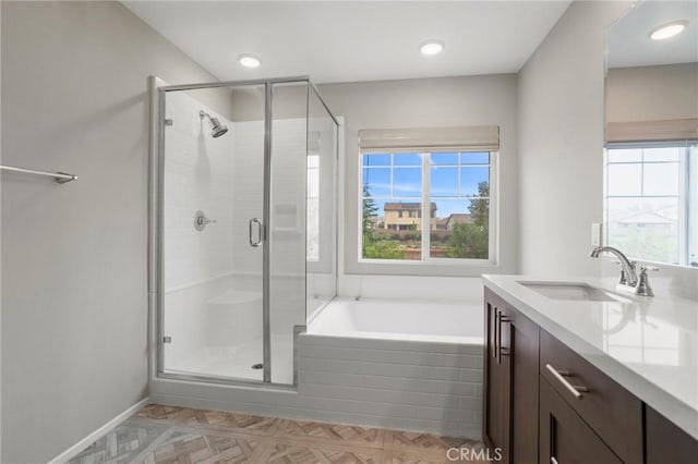 bathroom with vanity, baseboards, a bath, and a shower stall