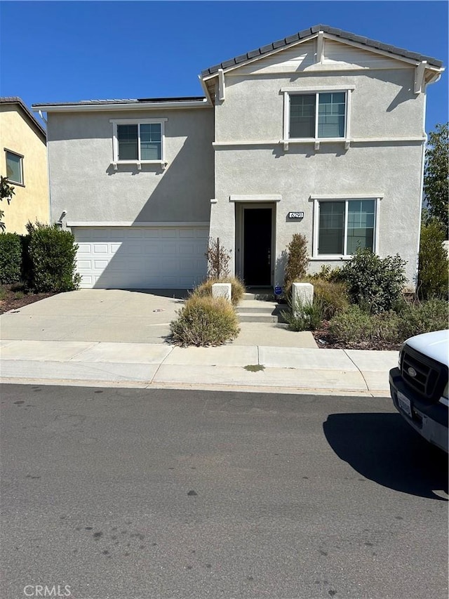 traditional home with an attached garage, stucco siding, and driveway