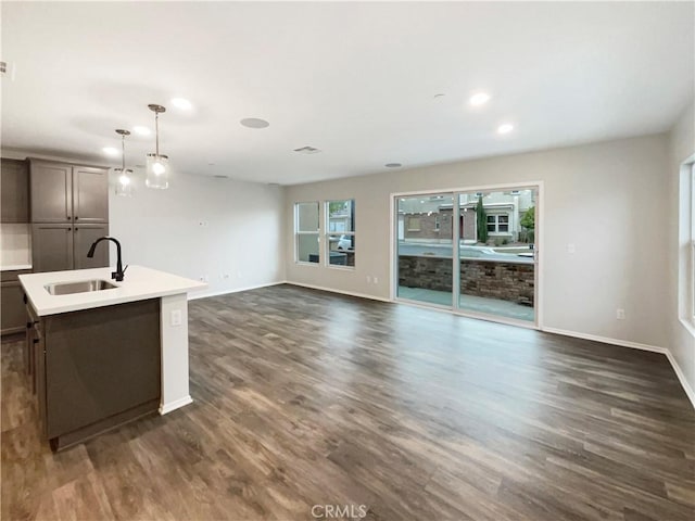 kitchen with a sink, baseboards, dark wood-style floors, and light countertops