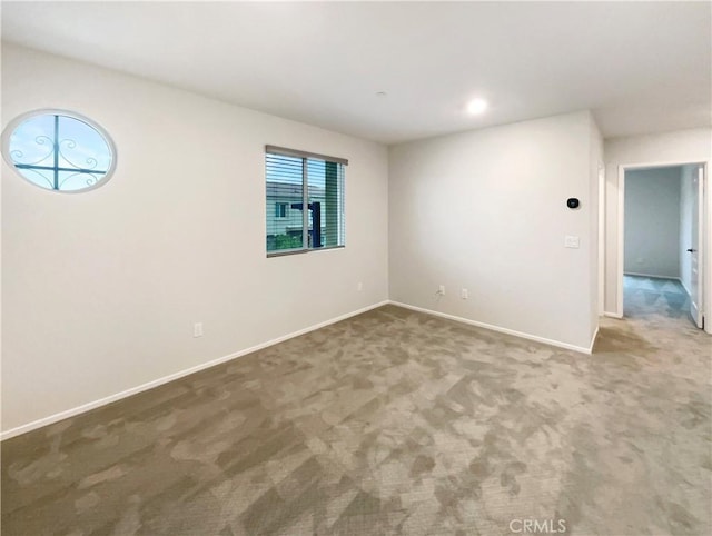 carpeted spare room featuring baseboards and plenty of natural light
