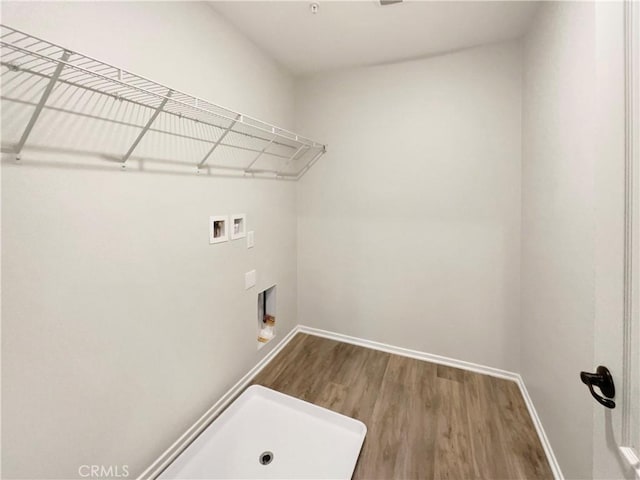 clothes washing area with baseboards, laundry area, hookup for a washing machine, and wood finished floors