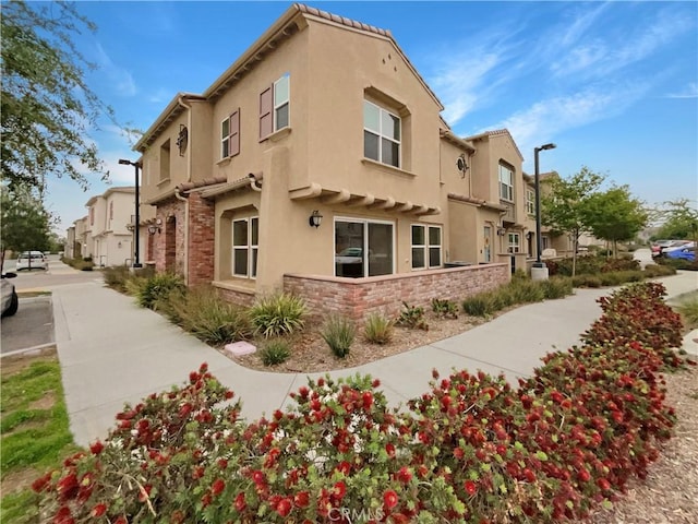view of side of property featuring a residential view, stucco siding, and stone siding