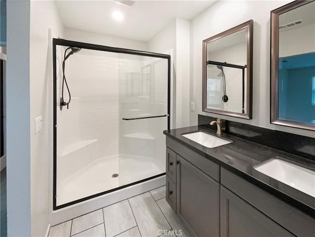 bathroom with double vanity, visible vents, a shower stall, and a sink