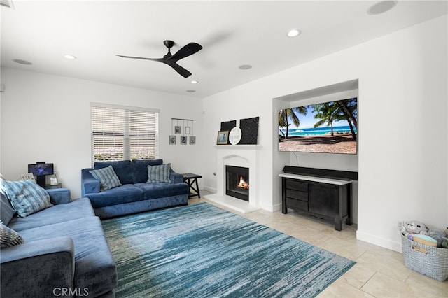 living room featuring ceiling fan, a lit fireplace, light tile patterned flooring, recessed lighting, and baseboards