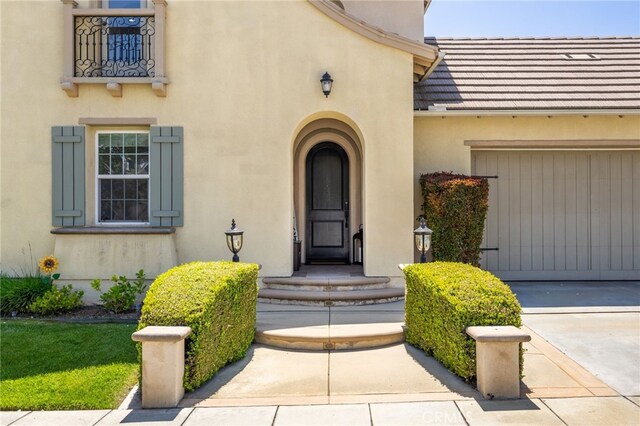 1526 Cole Ln, Upland, CA 91784 - view of exterior entry featuring stucco siding, driveway, a balcony, and an attached garage