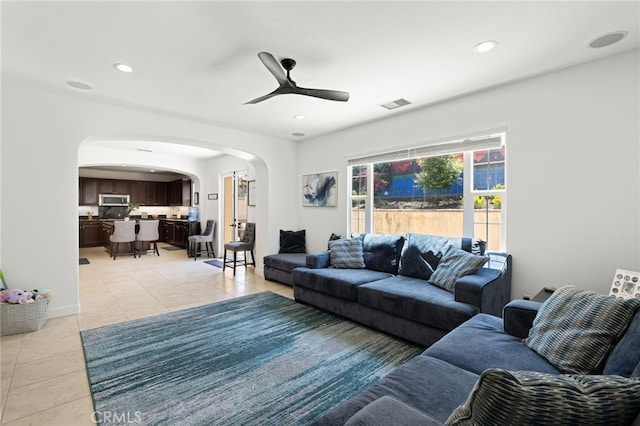 living room with arched walkways, light tile patterned floors, ceiling fan, and recessed lighting