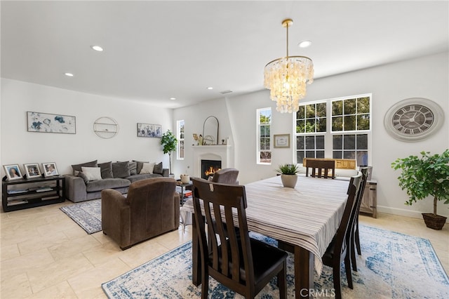 dining area with recessed lighting, a chandelier, a warm lit fireplace, and light tile patterned floors