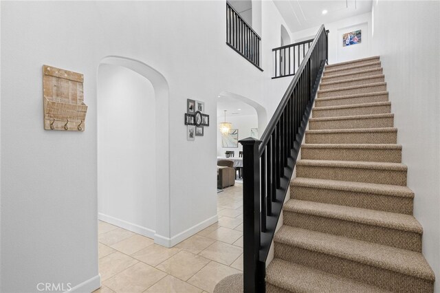 1526 Cole Ln, Upland, CA 91784 - staircase featuring arched walkways, tile patterned flooring, baseboards, and a high ceiling