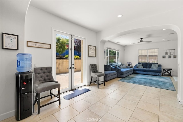 living area with arched walkways, a ceiling fan, light tile patterned floors, and recessed lighting