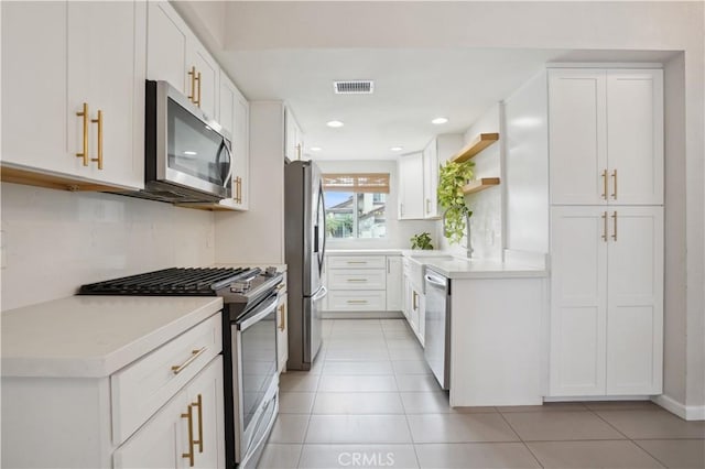 kitchen featuring white cabinets, open shelves, appliances with stainless steel finishes, and light countertops
