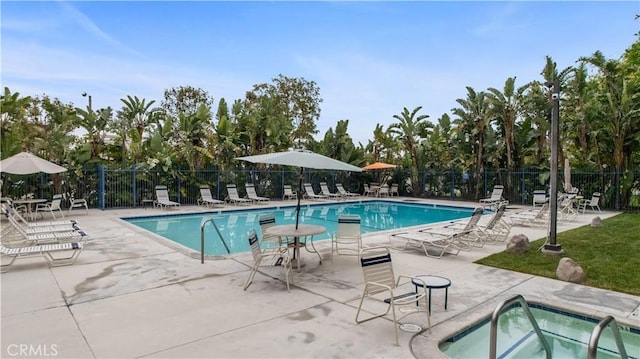 pool with a community hot tub, a patio area, and fence