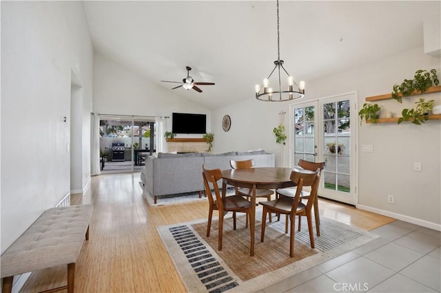 dining space featuring high vaulted ceiling, plenty of natural light, baseboards, and ceiling fan with notable chandelier