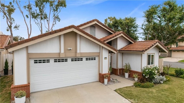 view of front of property featuring a garage, stucco siding, brick siding, driveway, and a tile roof