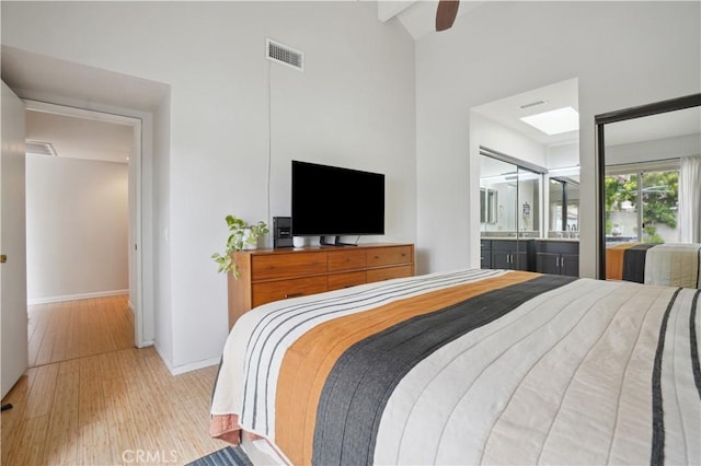 bedroom with visible vents, baseboards, high vaulted ceiling, connected bathroom, and light wood-style flooring