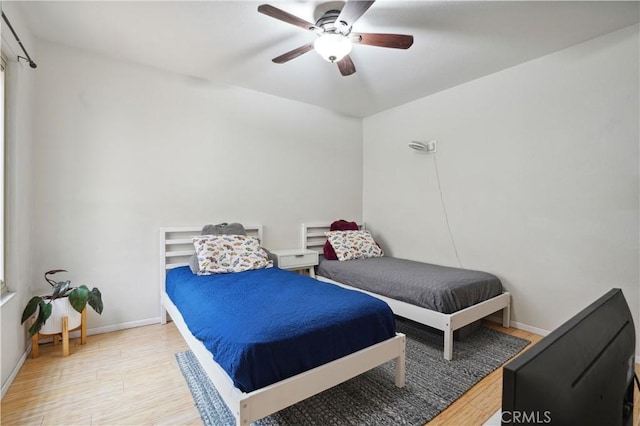 bedroom featuring baseboards, a ceiling fan, and wood finished floors