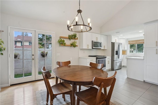 dining space featuring a chandelier, french doors, and vaulted ceiling